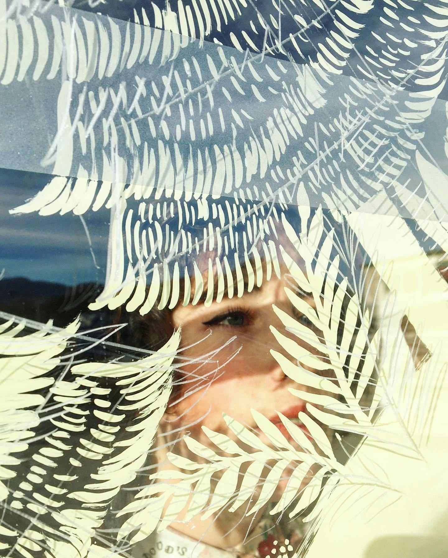 Portrait of Margot Reverdy painting leaves on a window.