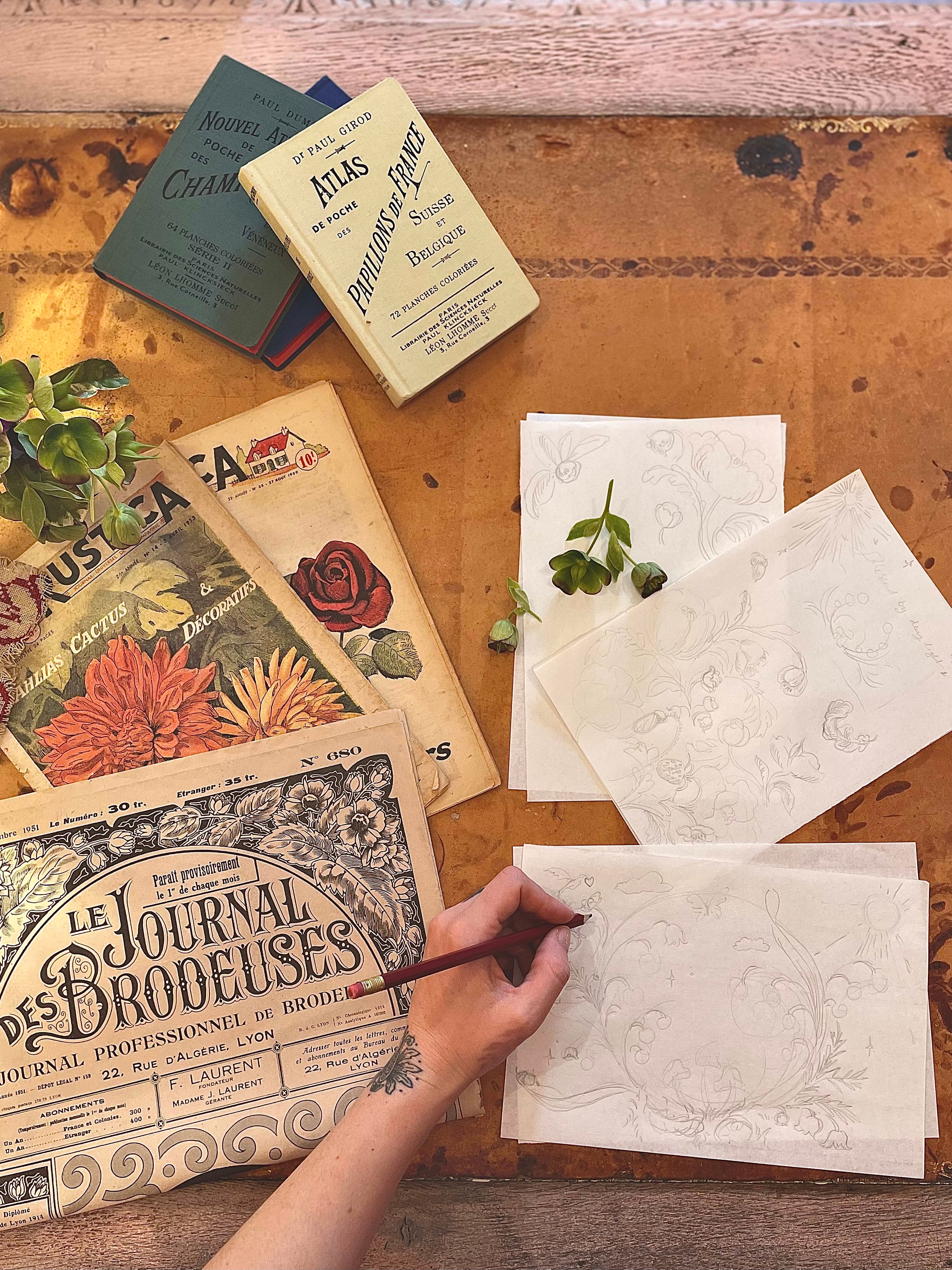 Artist drawing by hand with stylus across scattered working papers