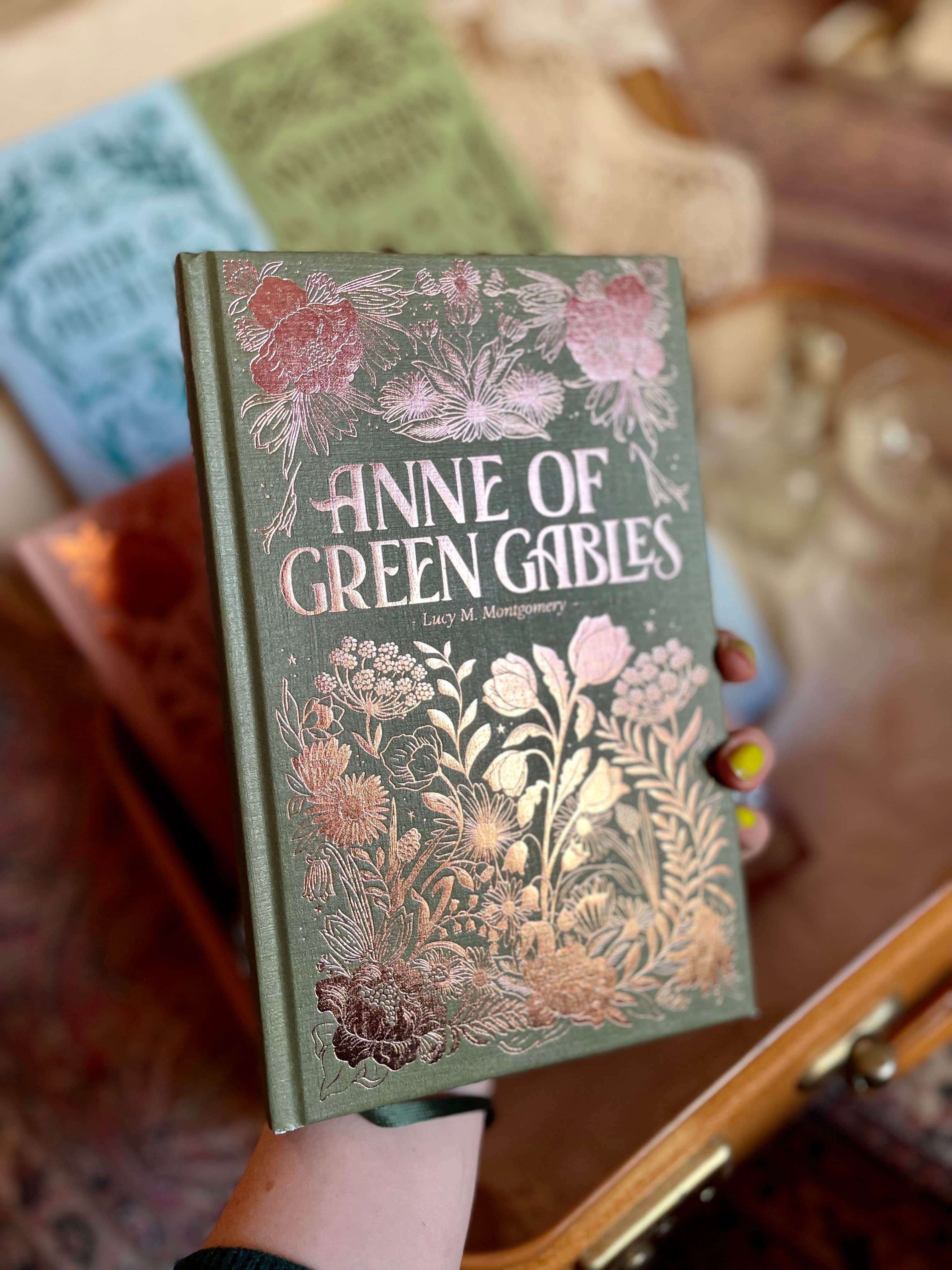 Hand holding a book with a densely illustrated floral cover design for Anne of Green Gables special edition.