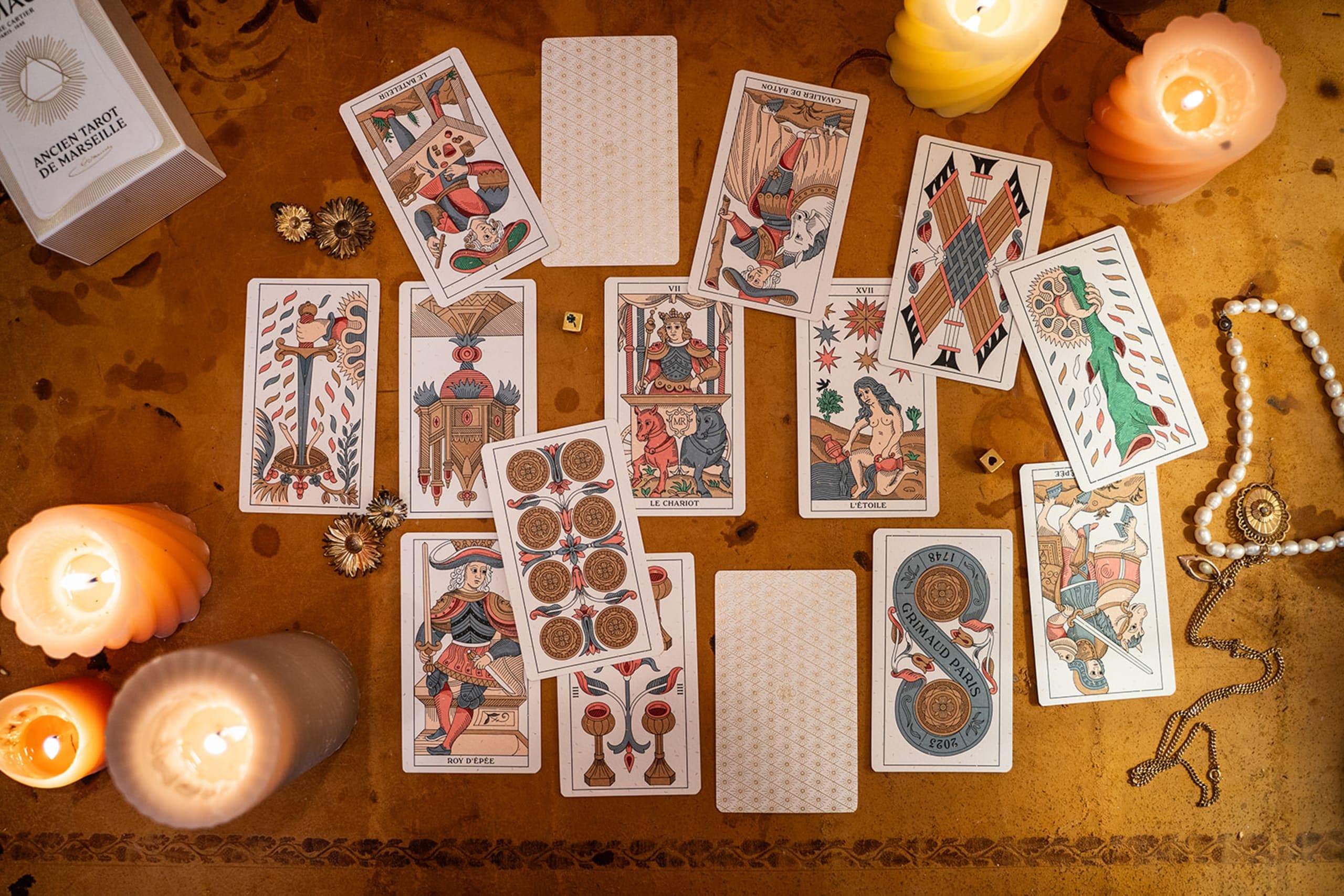 Tarot de Marseille cards spread across a table with candles