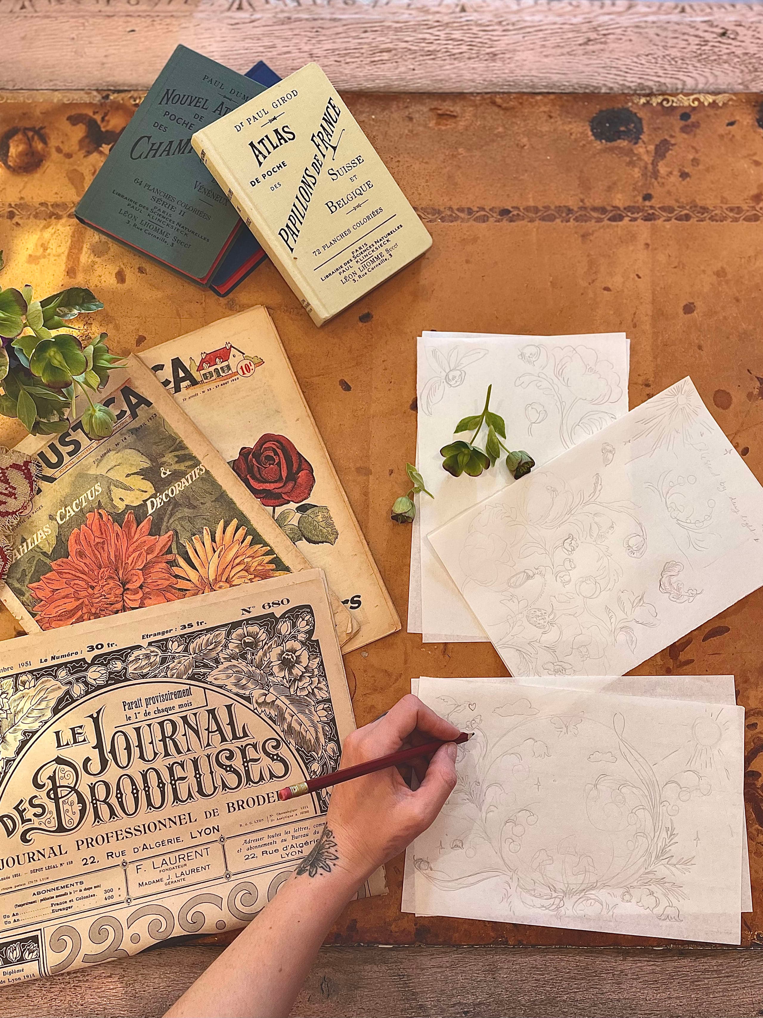 Artist drawing by hand with stylus across scattered working papers