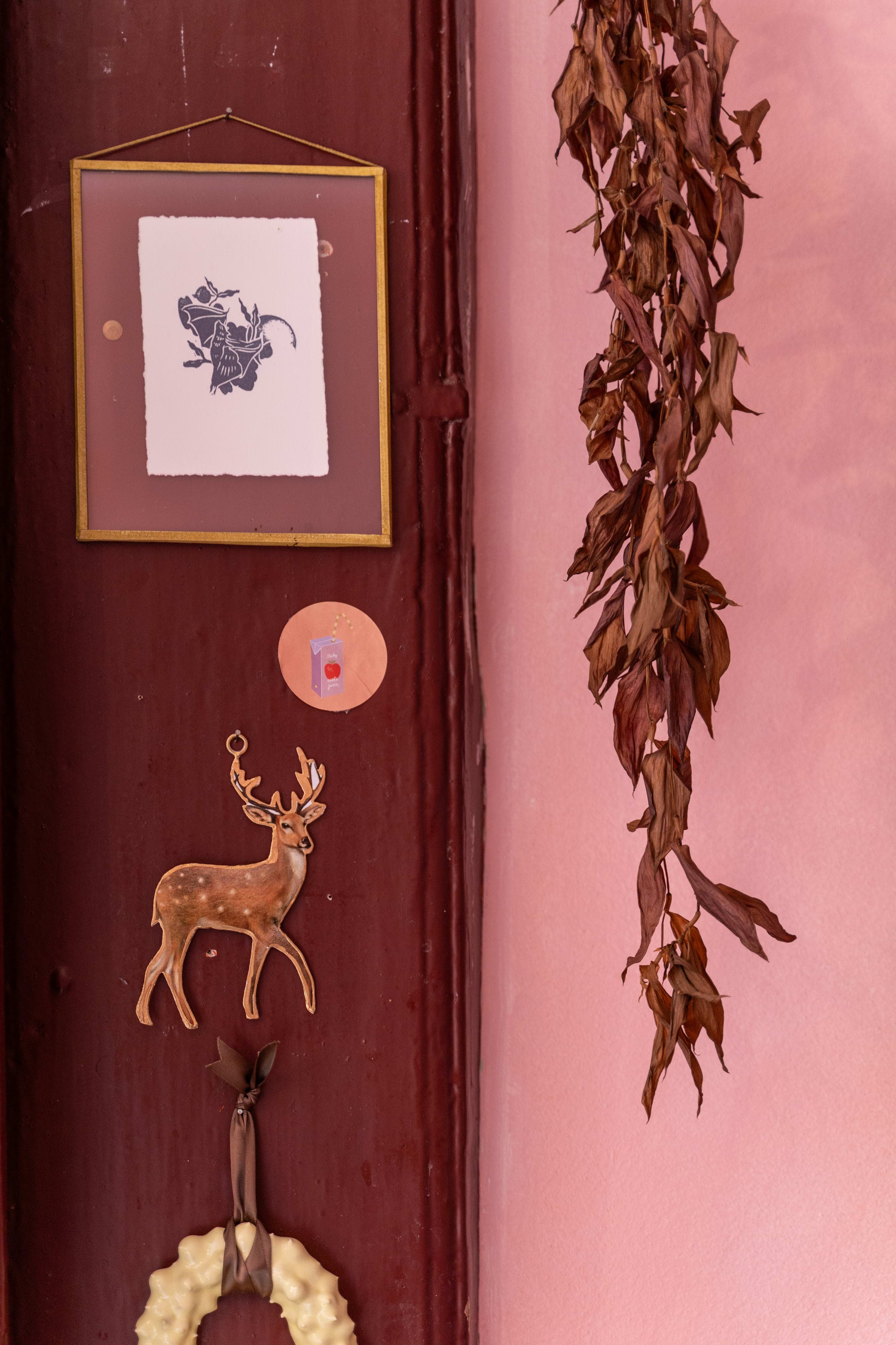 Etching-style botanical illustration of a deer and floral wreath on a studio door