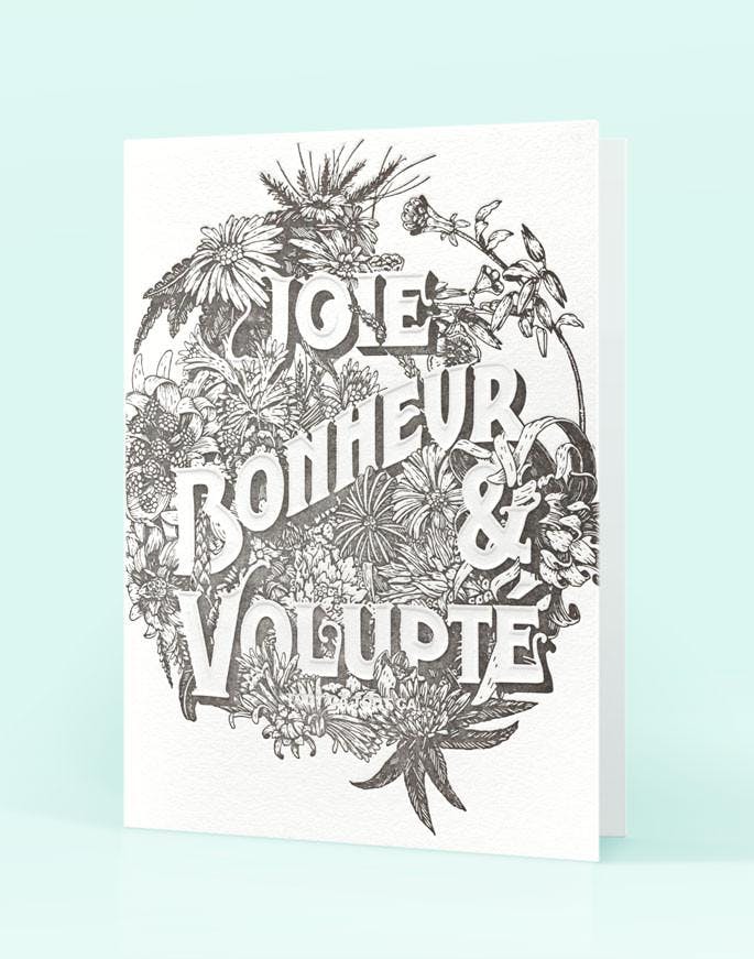 Joie Bonheur & Volupté letterpressed card on a blue background